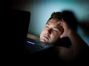 A man, looking tired and overwhelmed, looks at his laptop. He has decided to start anxiety treatment with Barton Counseling Services in Katy, TX 77494